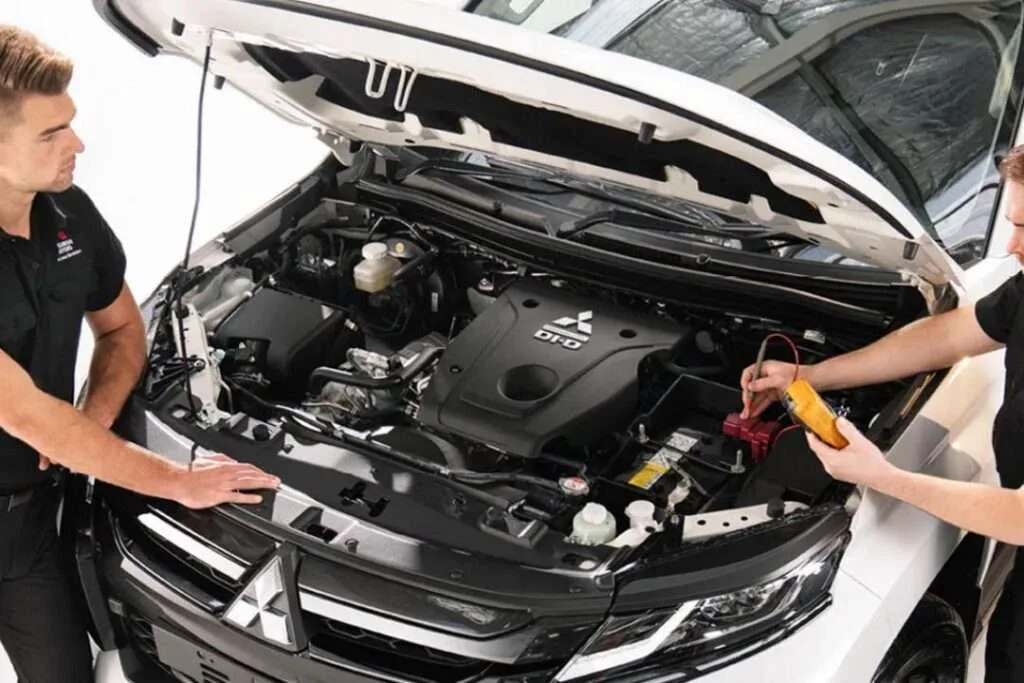 Mechanic checking voltage before battery replacement in a Mitsubishi