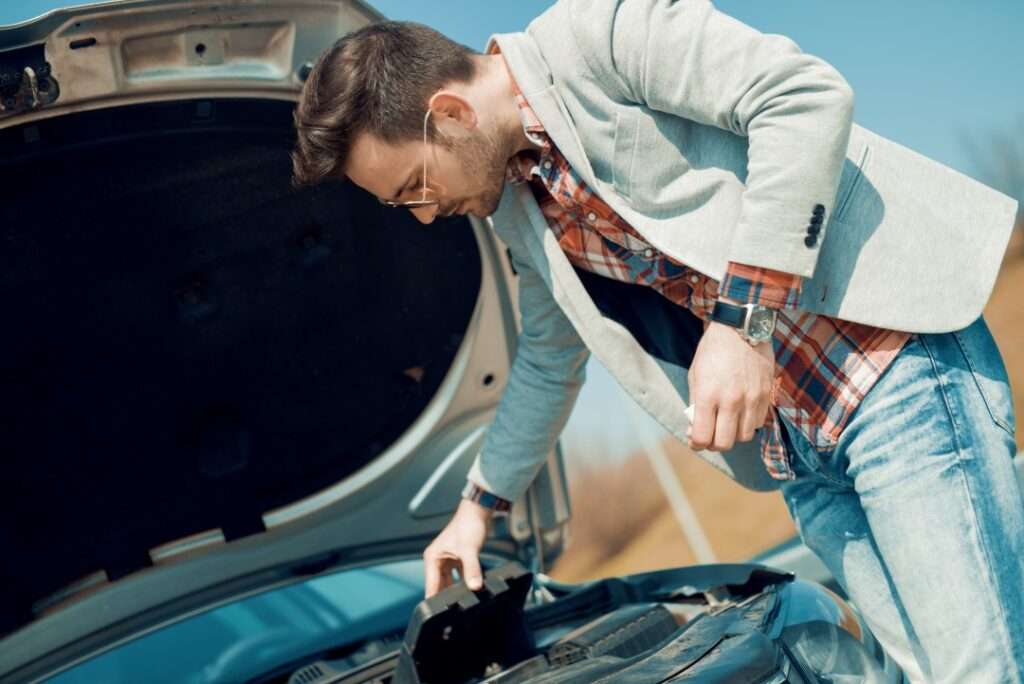 Skilled technician replacing the battery of a Porsche sports car using quality tools